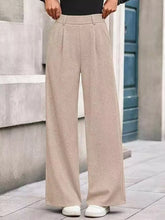 Beige wide-leg pants with high waist and pleated front in soft textured fabric, machine wash care instructions included