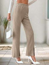 Beige high-waisted slit pants featuring a wide-leg design with side slits and an elastic waistband for comfort