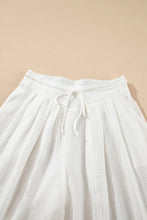 White flowing wide leg tie waist pleated pants with elastic waistband and matching drawstring for comfortable wear