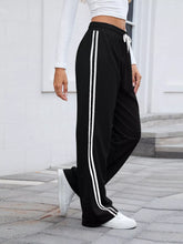 Black striped wide leg pants with two white vertical stripes and matching drawstring waistband for athletic use