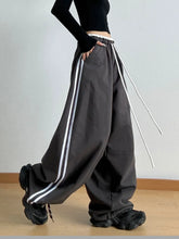 Dark gray wide leg drawstring pants with white side stripes and adjustable leg drawstring for casual wear