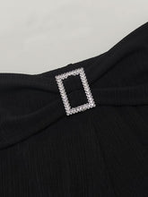 A sparkling silver rhinestone buckle adorns the black fabric of plus size high-waisted flare pants