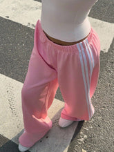Pink adidas wide leg pants with white stripes down the side in a comfortable track pant design
