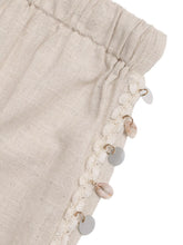 Beige linen drawstring wide leg pants with gathered waistband and decorative white lace seashell and bead trim