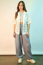 A woman wearing gray very j wide leg gauze solid pants paired with a light blue and white lace open-front jacket