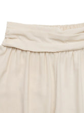 Beige pleated skirt with elastic waistband styled with ruched high waist joggers for a versatile look
