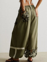 Olive green linen drawstring harem pants featuring floral lace appliqués on pockets and hem for elegant style