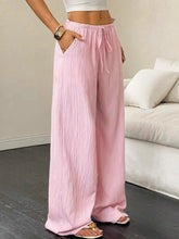 Soft pink tied wide leg pants with drawstring waist and subtle vertical pleats for a stylish comfortable fit