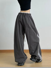 Dark gray wide leg drawstring pants with white side stripes and elastic waistband for comfortable wear