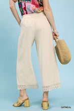 Cream-colored umgee linen wide leg cropped pants featuring delicate lace trim at the hem