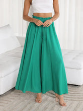 Emerald green wide leg pants with high-waisted ruffled elastic waistband and drawstring pockets detail