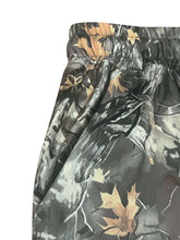 Relaxed fit camo print sweatpants with drawstring waist featuring dark green brown and tan camouflage leaves and branches
