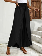 High-waisted side slit black polyester pants with wide-leg flow and drawstring waistband, machine wash care instructions
