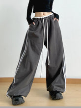 Dark gray wide leg drawstring pants with white side stripes and a comfortable drawstring waistband for casual wear