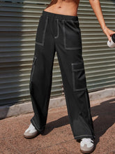 Black wide leg pants with white contrast stitching and multiple pockets in durable cargo style