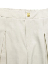 Beige slit wide leg pleated pants featuring a gold-toned textured button at the waistband