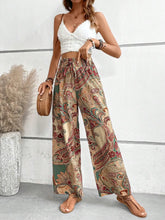 Printed wide leg pants with high waist and vibrant paisley pattern in earthy beige red and green on lightweight fabric