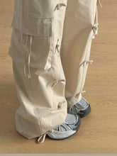 Beige cargo wide leg pants with multiple pockets and drawstring bow tie details for a casual stylish look