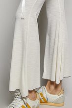 Cream-colored wide-leg textured ribbed knit pants with subtle pattern and white drawstring ribbon at the waist