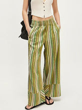 Striped high-waisted wide leg pants with vertical stripes in green yellow and brown featuring care instructions