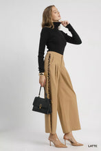 Black structured handbag with gold-tone clasp and chain detail paired with umgee pleated wide-leg pants with contrast trim