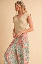 Beige sleeveless top with v-neckline and ruched detailing paired with aemi+co printed wide leg pants