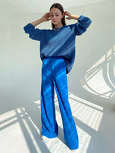 Blue ribbed knit sweater paired with wide leg pleated pants showcasing care instructions on label