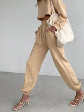 Beige cropped sweatshirt with drawstring waist and relaxed fit paired with casual drawstring jogger pants