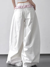 White wide leg drawstring casual pants featuring a pink ruffled waistband for comfortable stylish wear