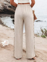 Beige linen drawstring wide leg pants with decorative tassel trim along the side seams for a stylish look