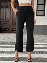 Black high-waisted pearl-embellished cropped wide-leg pants in sleek stretchy fabric with decorative studs along the hem