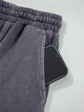 Dark gray flower patch mineral washed terry knit cropped wide leg pants with elastic waistband and front pocket holding smartphone