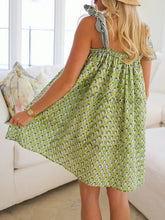 Green floral summer dress with ruffled straps, bow detail, and pearl necklace