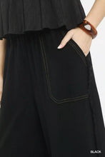 Black linen wide leg pants with frayed side pockets and contrasting white stitching along pocket edges