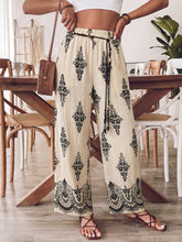 Beige boho print wide leg pants with black floral lace patterns and elastic waistband with drawstring ties