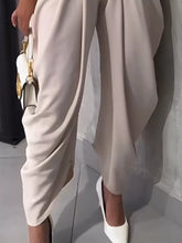 A sleek off-white satin handbag with gold hardware and pearl accent paired with high-waisted wide leg pleated pants