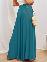 Teal wide leg pants with an elastic waistband featuring flowing fabric and functional side pockets