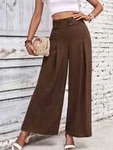 Brown high waisted wide leg pants with a black rectangular buckle and subtle pleats for a stylish look
