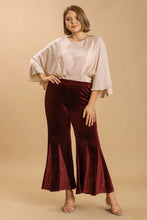 A pair of plus size burgundy velvet flare leg pants with size sequin elastic waistband and shimmer seams