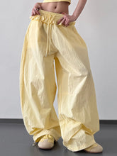 Pale yellow wide leg pants with a ruffled waistband and drawstring for comfortable, loose-fitting wear
