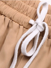 Beige wide leg drawstring casual pants with a soft pleated waistband and white braided cord tied in a knot