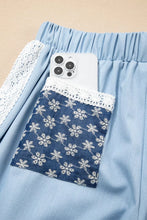 Light blue denim wide leg pants with lace accent floral patched pocket and embroidered snowflake detail
