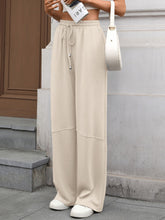 Beige drawstring high waist wide leg casual pants with elastic waistband and subtle seam detailing in relaxed fit