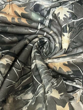 Relaxed fit camo print drawstring waist pants made of soft textured fabric with muted green brown and beige leaves