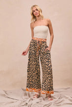 BiBi leopard print wide-leg pants with orange trim and drawstring waistband in bold leopard print design