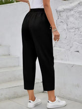 Black high rise elastic waist high trousers with cropped fit and subtle side button details for comfortable wear