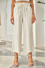 Cream-colored drawstring paperbag waist wide leg pants featuring a high-waisted design and comfortable fit