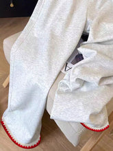 Light gray heathered casual loose fit sweatpants with red scalloped trim at cuffs and embroidered details