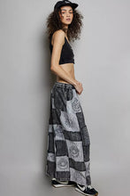 Black and white patchwork wide leg pants with drawstring waist featuring intricate paisley and sun motifs