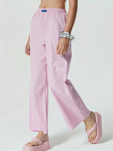 Pink high-waisted wide leg pants with an elastic waist and small blue brand tag for comfortable wear